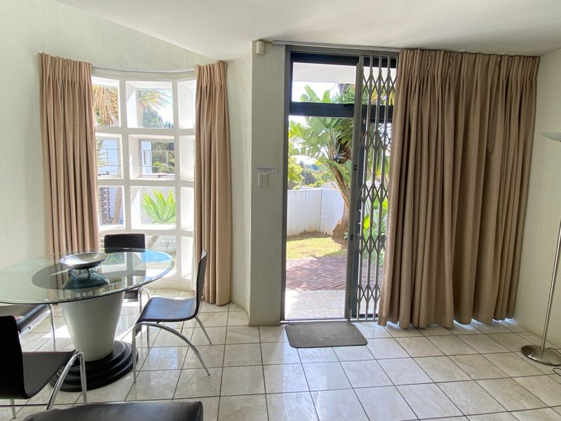 Bright dining area featuring tiled flooring, a large bay window, and a sliding glass door providing direct access to the outdoor patio area.