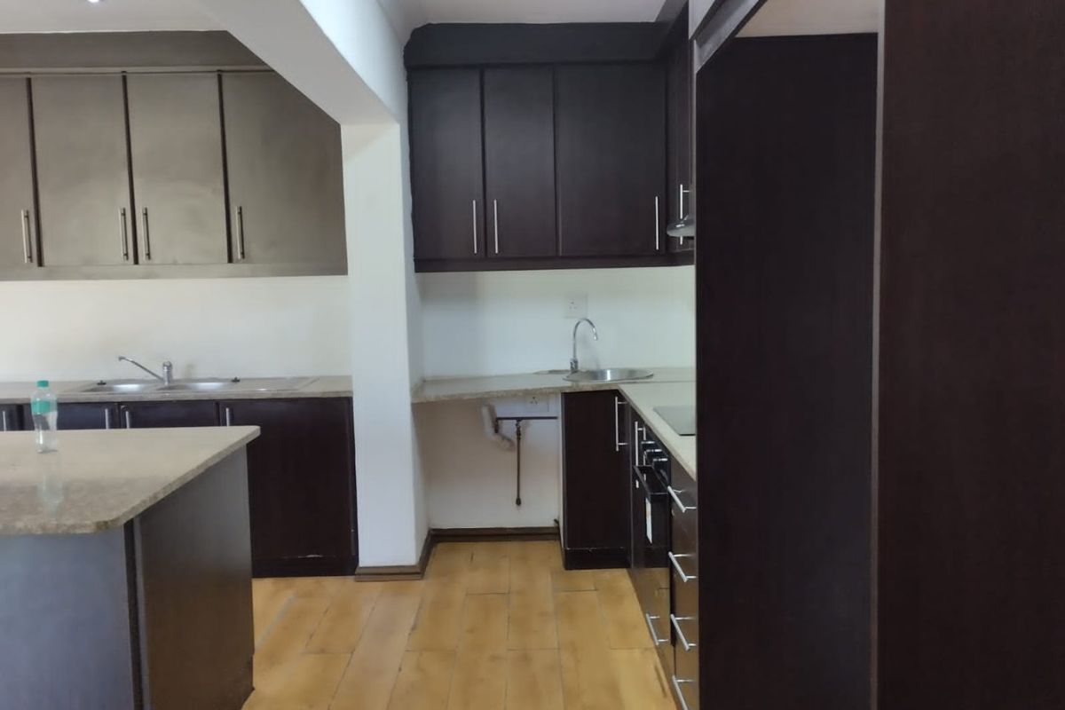 A functional kitchen featuring dark cabinetry, stone countertops, and integrated appliances, offering a clean and practical workspace.