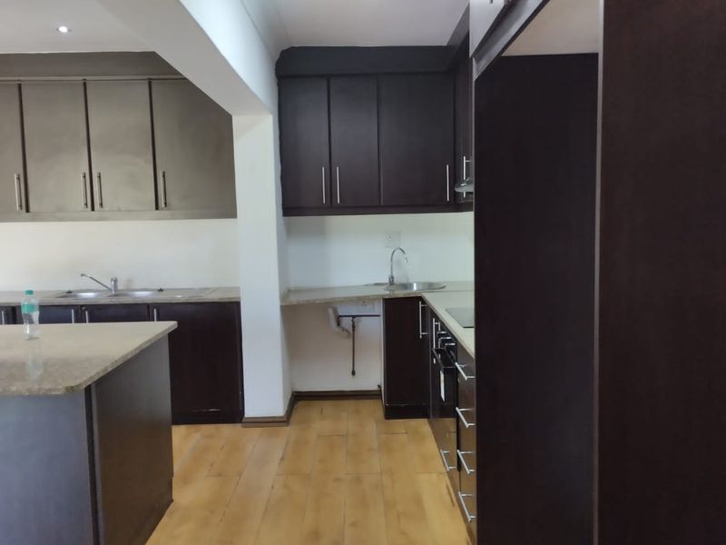 A functional kitchen featuring dark cabinetry, stone countertops, and integrated appliances, offering a clean and practical workspace.