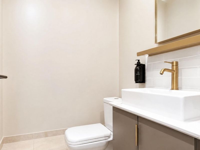 Modern guest bathroom featuring a sleek vanity with brass fixtures, subway tile backsplash, and a clean, contemporary design.