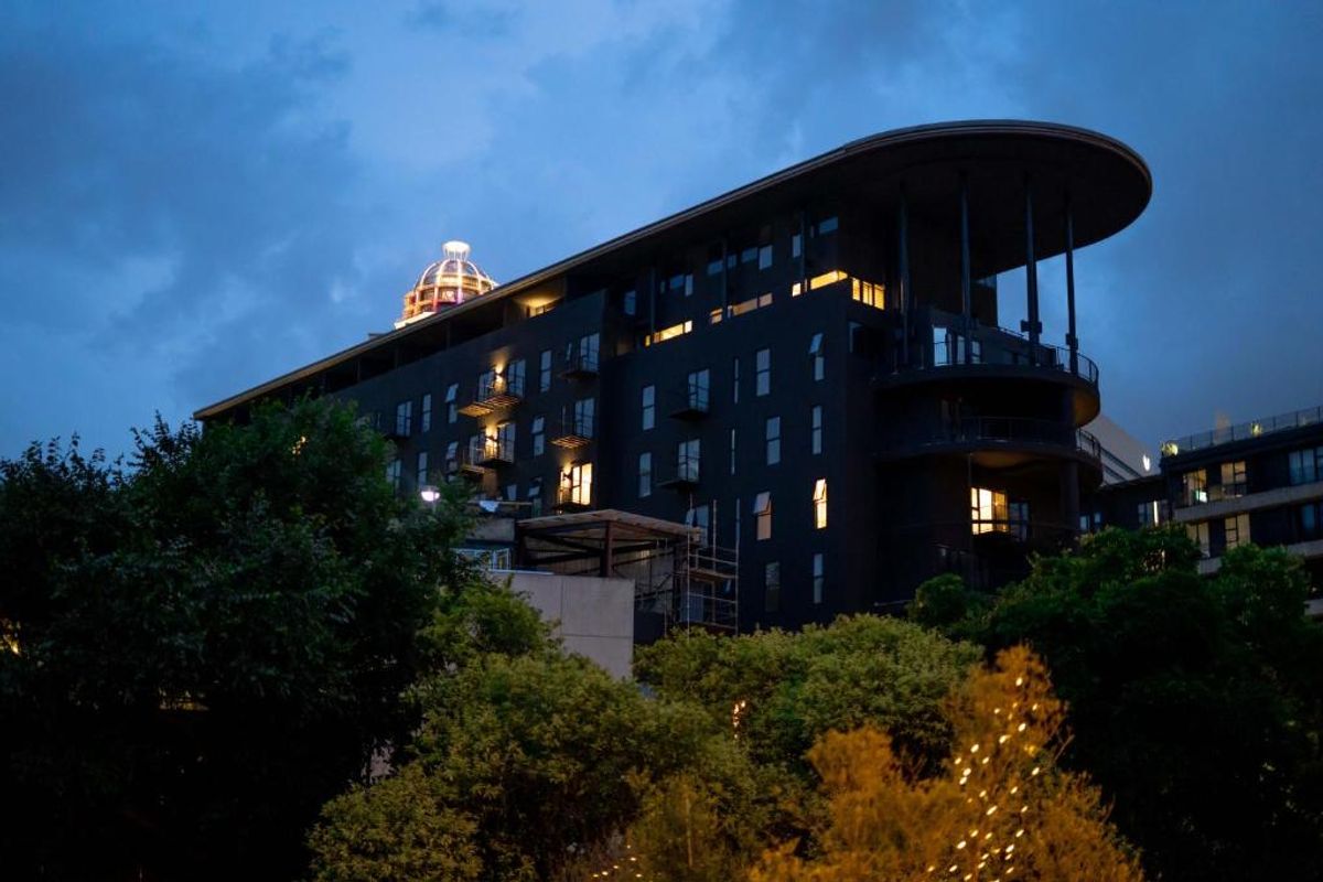 A dusk view of the apartment building exterior, showcasing its modern architectural design, balconies, and distinctive dome feature.
