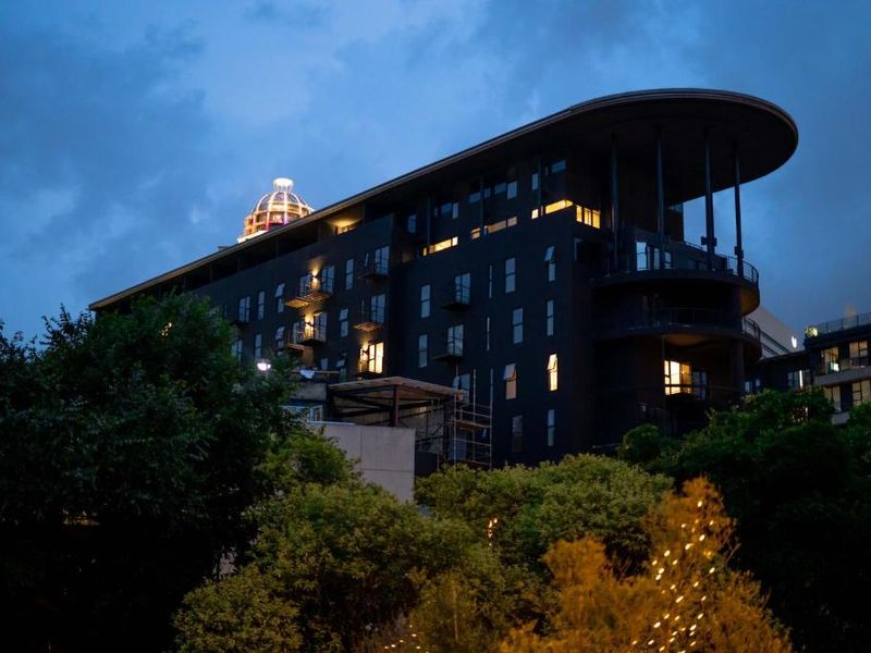 A dusk view of the apartment building exterior, showcasing its modern architectural design, balconies, and distinctive dome feature.