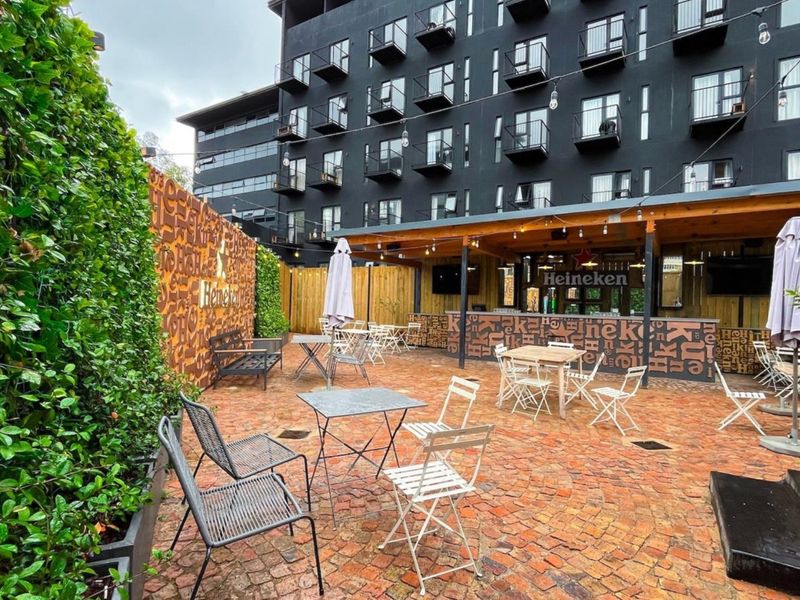 An outdoor patio area featuring a covered bar structure, paved flooring, and a vertical garden wall, suitable for social gatherings.