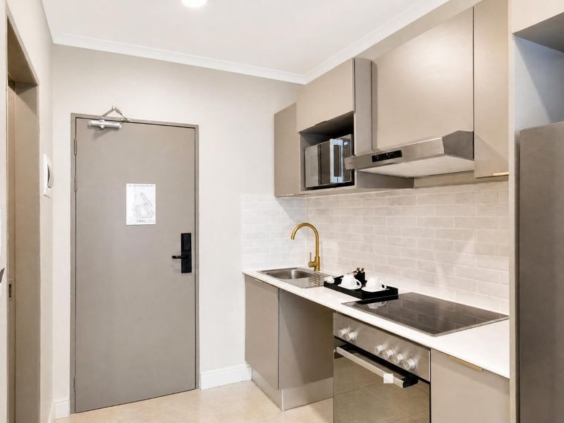 Modern compact kitchen featuring sleek cabinetry, stainless steel appliances, subway tile backsplash, and a stylish brass faucet.