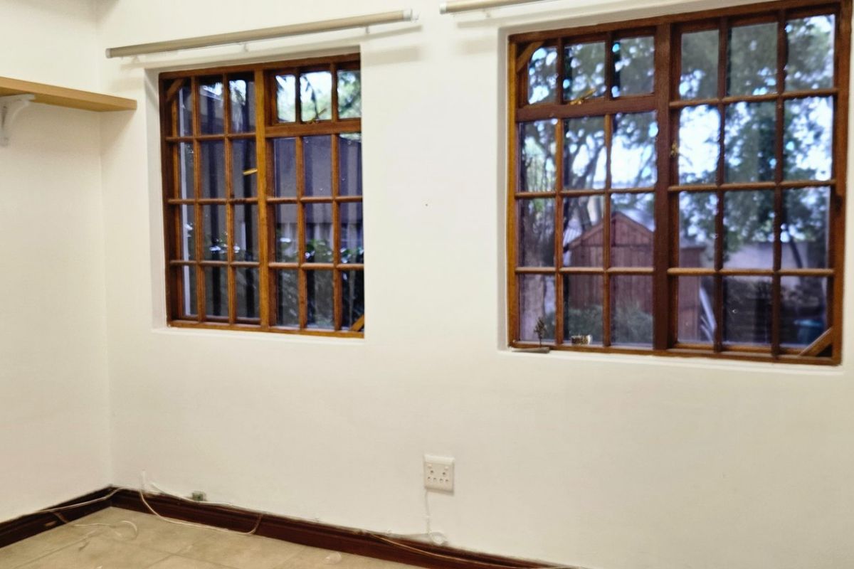 An empty bedroom featuring tiled flooring, timber-framed windows, and wall-mounted shelving, providing a blank canvas for personalization.