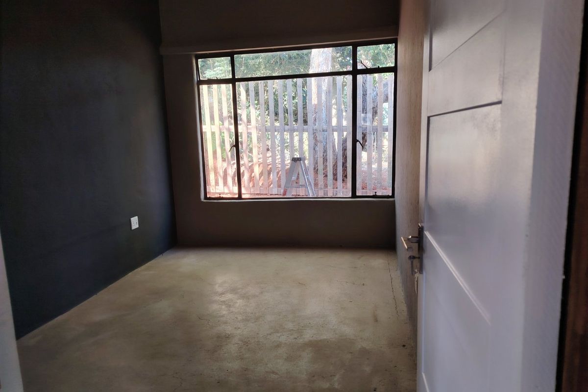 An empty bedroom featuring concrete flooring, a large window, and dark painted walls, offering a blank canvas for renovation.