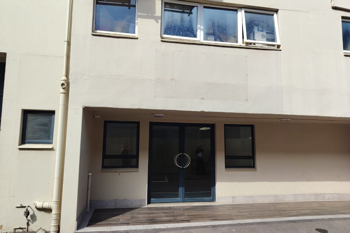 Front entrance of an industrial building featuring double glass doors, aluminium framed windows, and a tiled landing area.