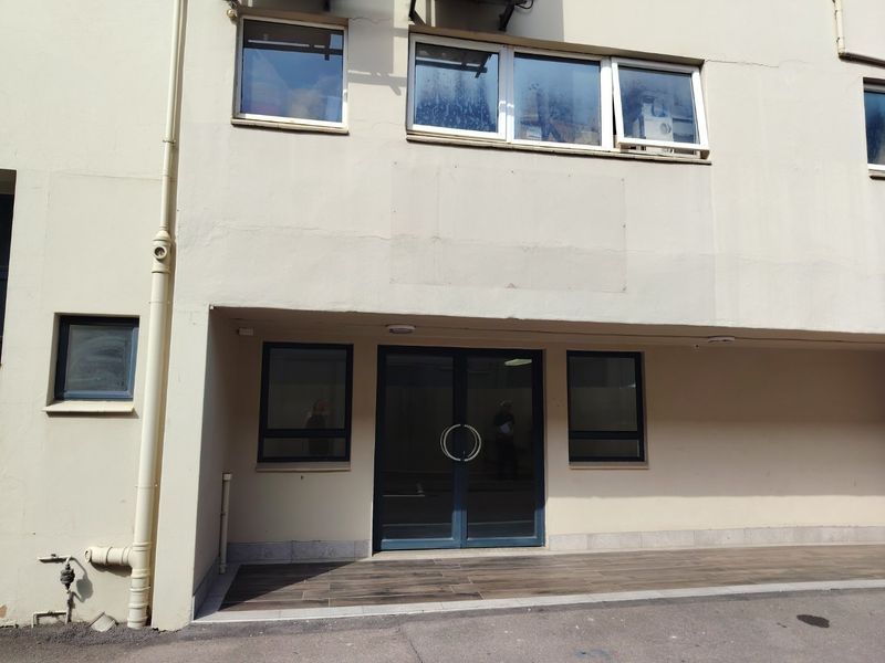 Front entrance of an industrial building featuring double glass doors, aluminium framed windows, and a tiled landing area.