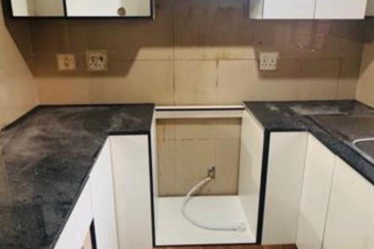 A compact kitchen featuring white cabinetry, dark stone countertops, and tiled flooring, currently awaiting appliance installation.