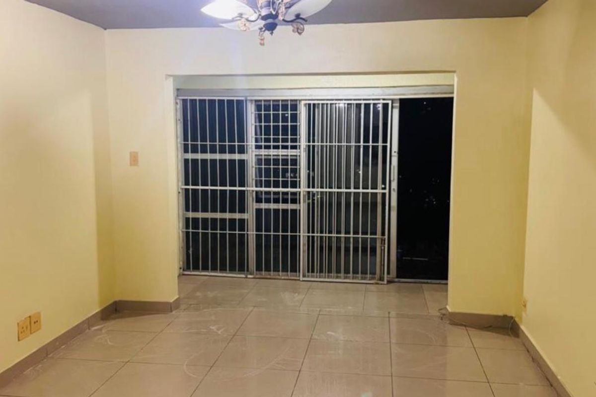 An empty living room featuring tiled flooring and a sliding glass door with an integrated security gate.