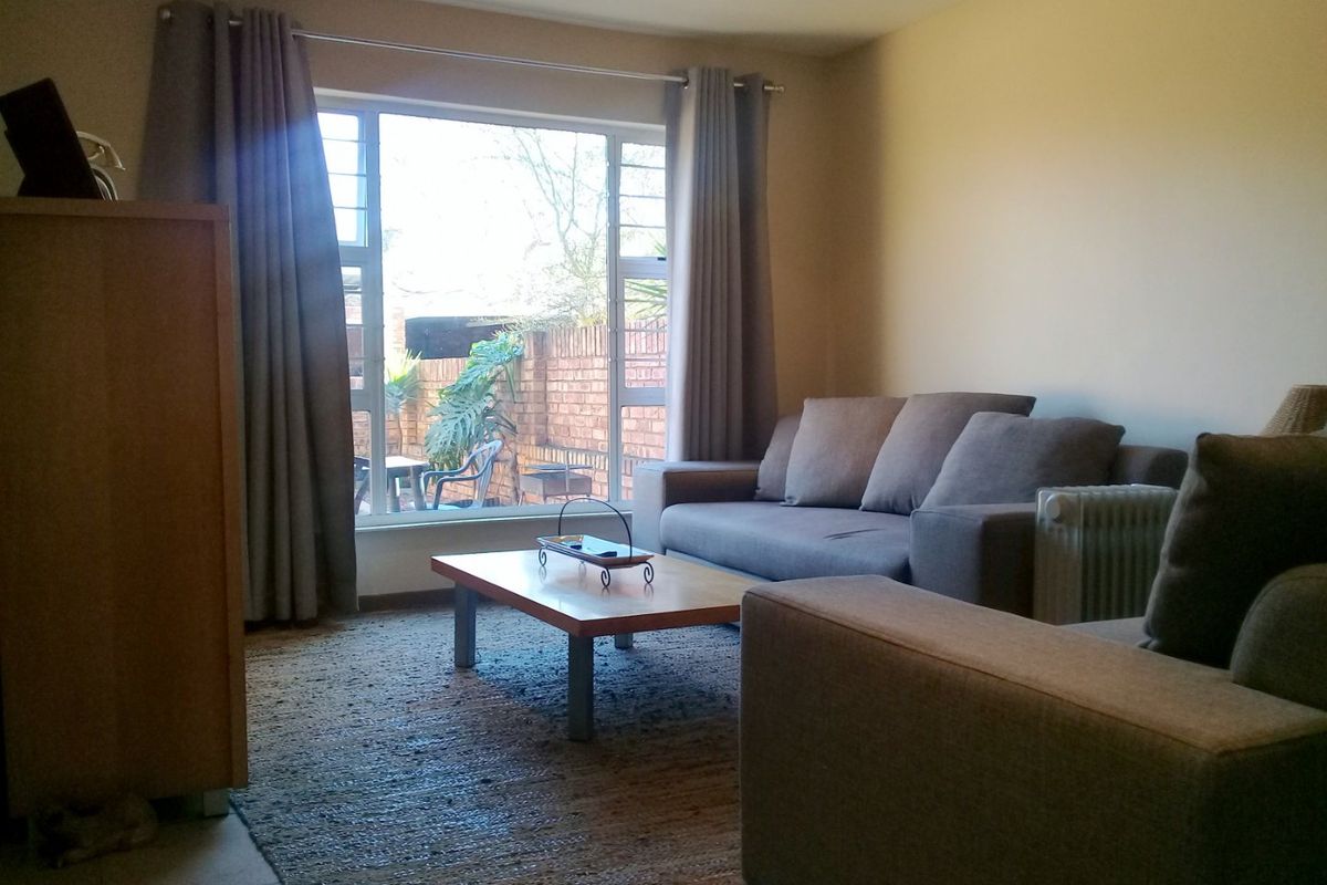 A comfortable living room featuring a large window with natural light and views of the rear garden area.
