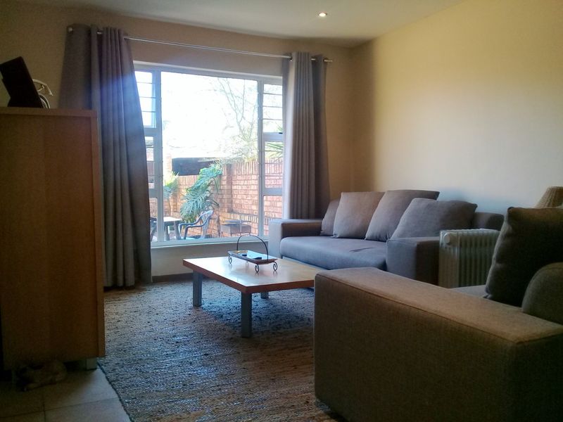 A comfortable living room featuring a large window with natural light and views of the rear garden area.