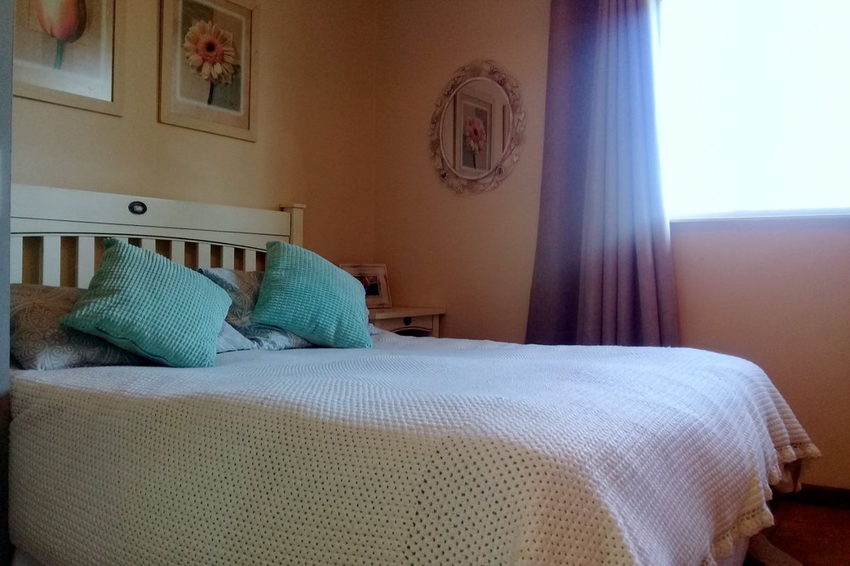 A cozy bedroom featuring carpeted flooring and a window with curtains, providing natural light.