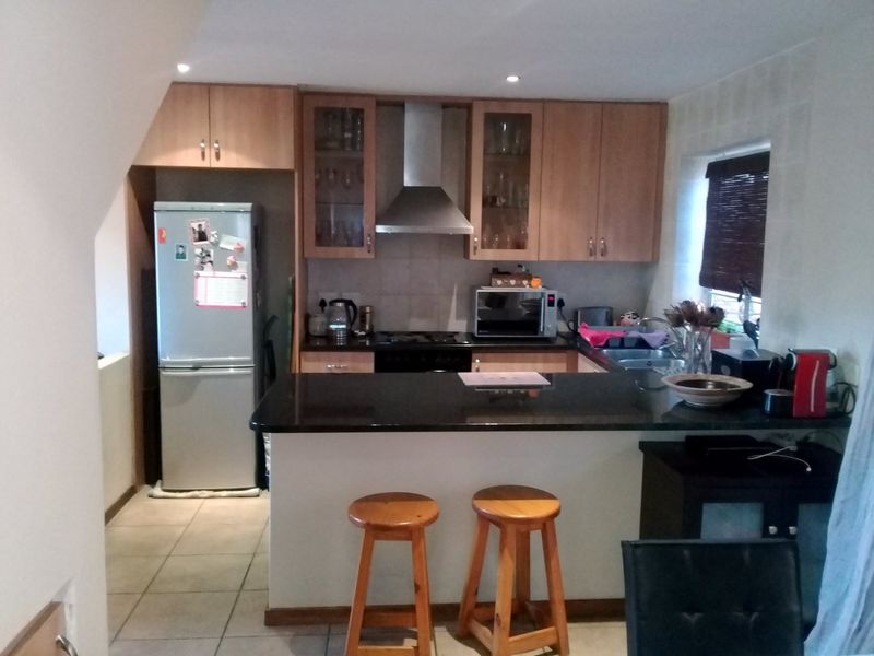 A functional kitchen featuring wooden cabinetry, granite countertops, a breakfast bar, and tiled flooring, providing a practical layout for daily cooking and dining.