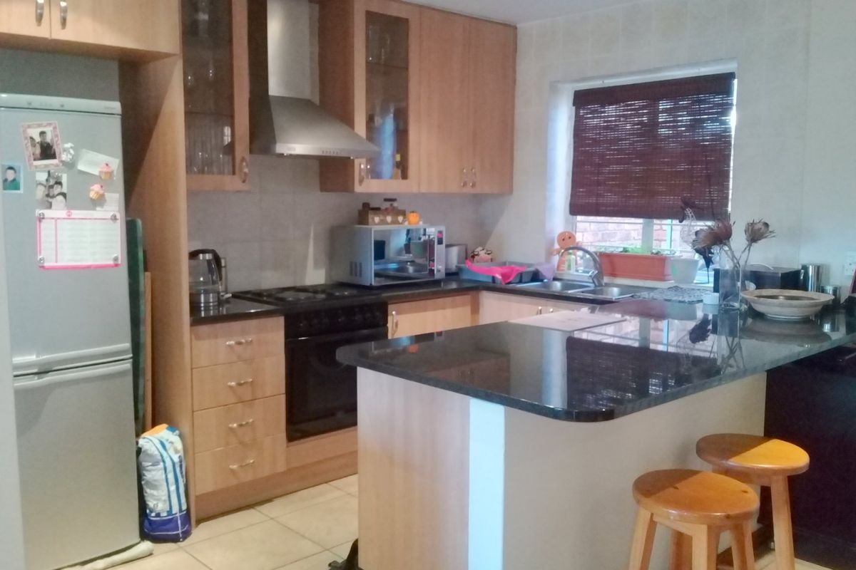 A functional kitchen featuring light wood cabinetry, dark granite countertops, a built-in oven with extractor fan, and a breakfast bar island.