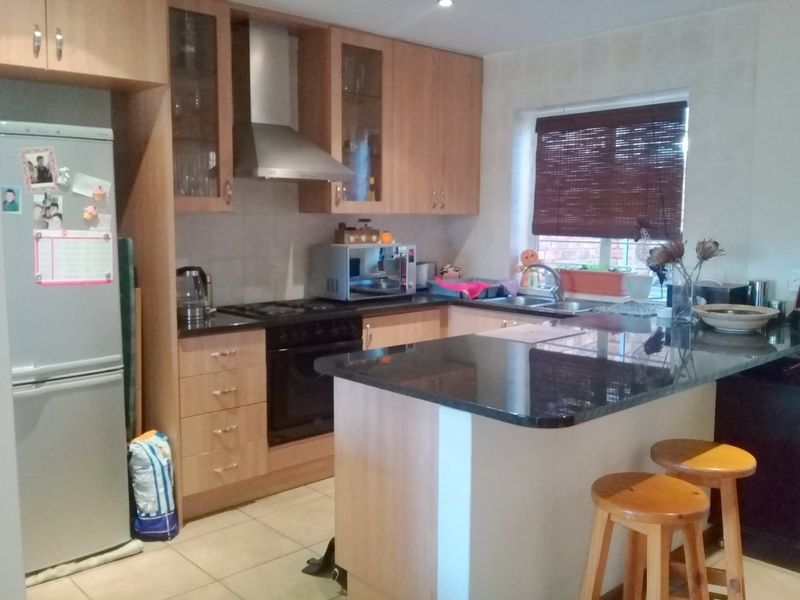 A functional kitchen featuring light wood cabinetry, dark granite countertops, a built-in oven with extractor fan, and a breakfast bar island.