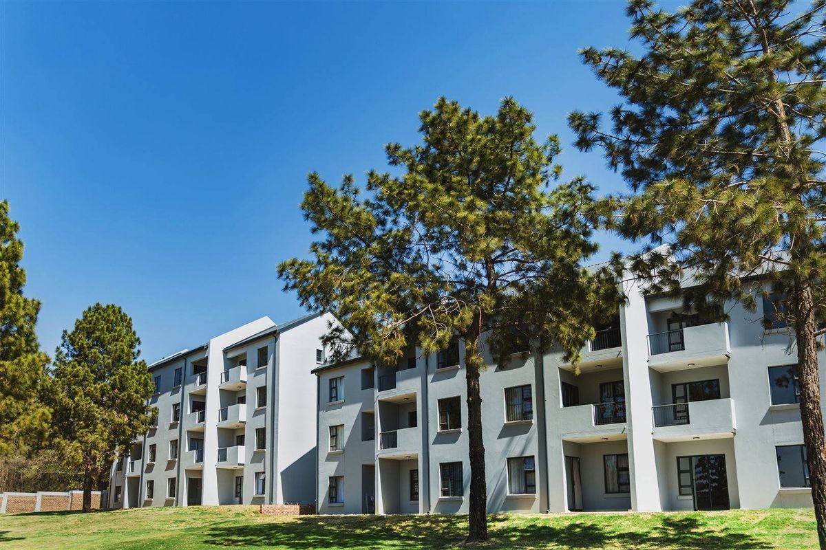 Exterior view of a modern apartment complex featuring multiple levels with private balconies and landscaped grounds.