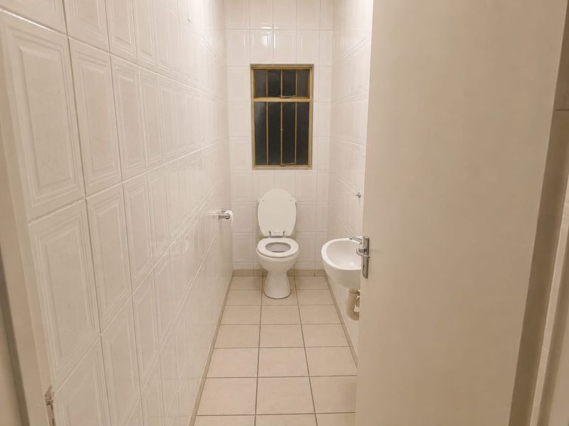 A compact guest bathroom featuring full-height wall tiling, a wall-mounted basin, and a standard toilet.