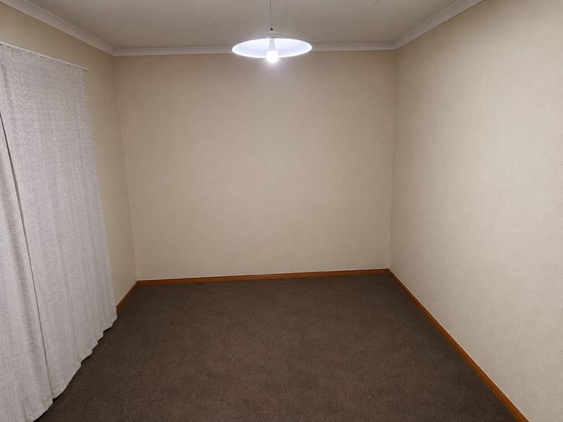 A clean, empty bedroom featuring neutral wall finishes, carpeted flooring, and simple overhead lighting, providing a blank canvas for personalization.