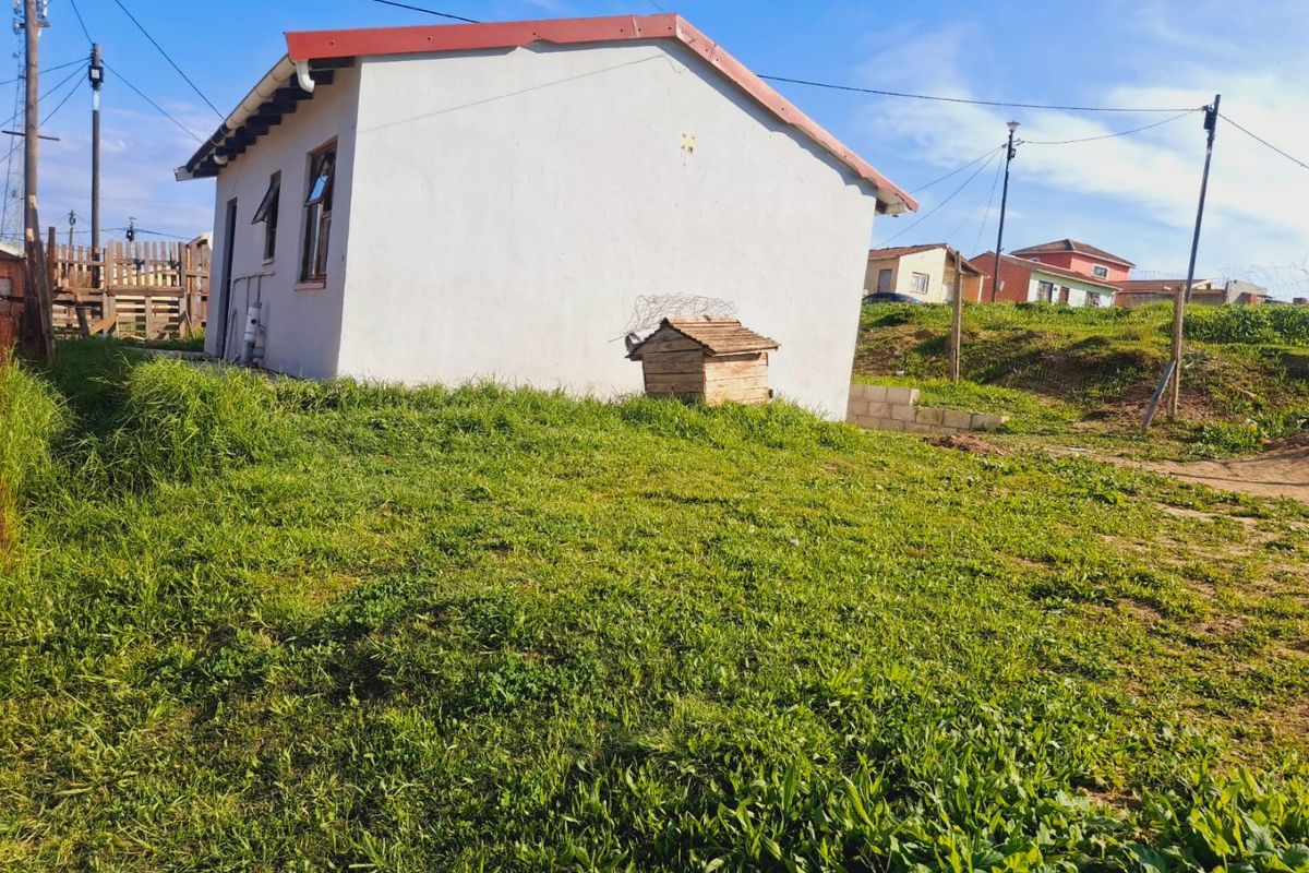 A view of the rear exterior of the house showing the side wall, roofline, and surrounding grass yard area.