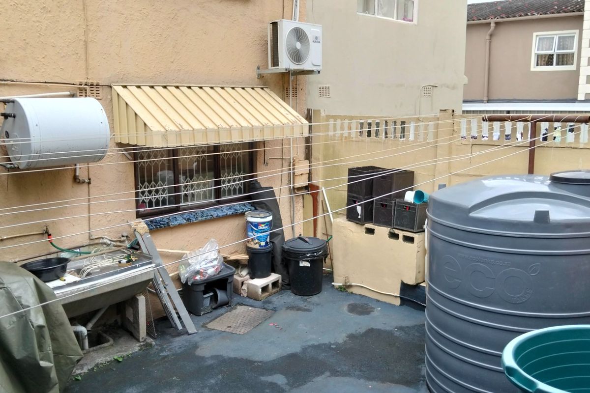 Rear utility area featuring a water storage tank, external water heater, air conditioning unit, and a fixed washing line setup.