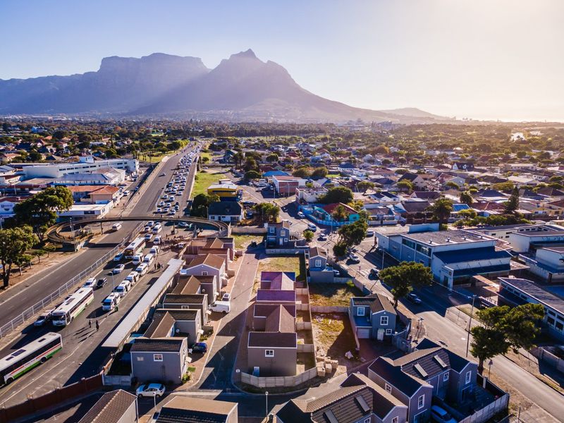 An aerial view of the surrounding neighborhood and urban landscape, featuring prominent mountain views and established road infrastructure.