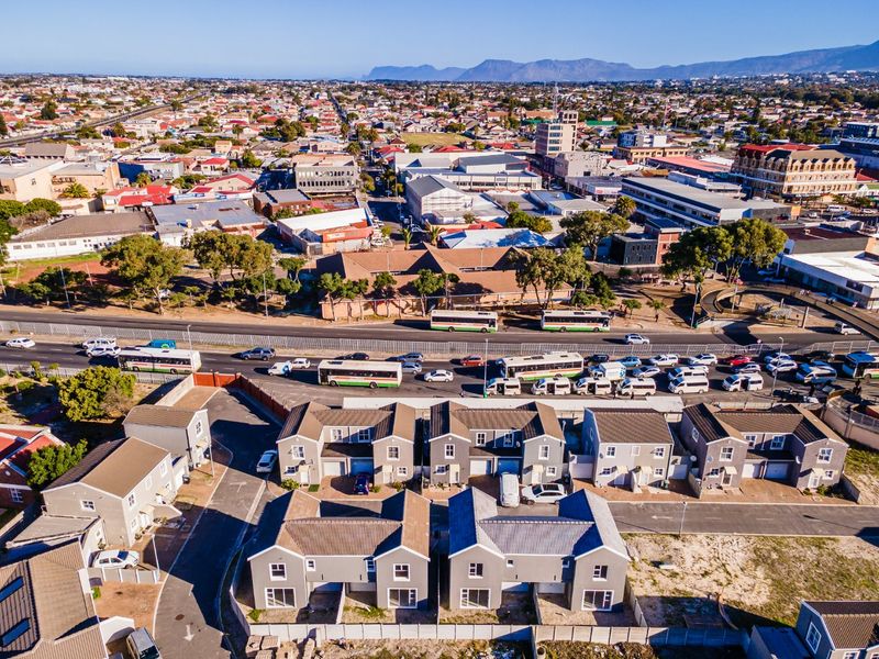 Aerial view of a modern residential townhouse complex situated in an urban environment with convenient access to main roads and local amenities.