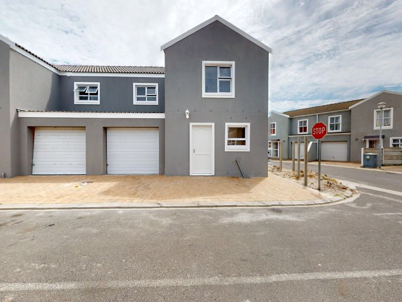 Front elevation of a modern two-story townhouse featuring a double garage, paved driveway, and neutral grey exterior finish.