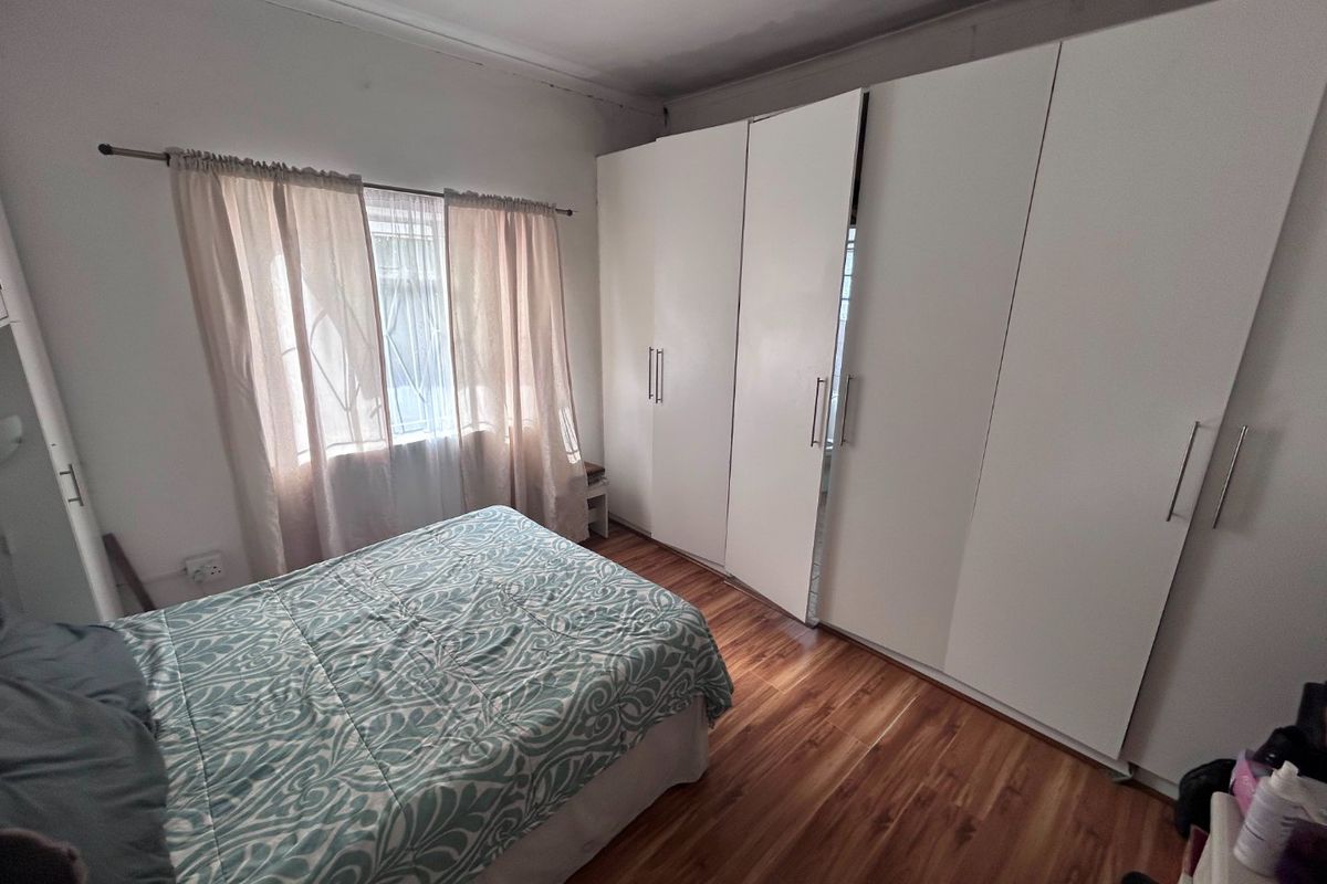 A bedroom featuring laminate flooring and extensive white built-in cupboards providing ample storage space.