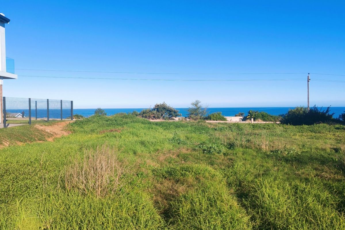A vacant residential plot featuring expansive ocean views and established perimeter fencing, offering a prime location for a new coastal home.