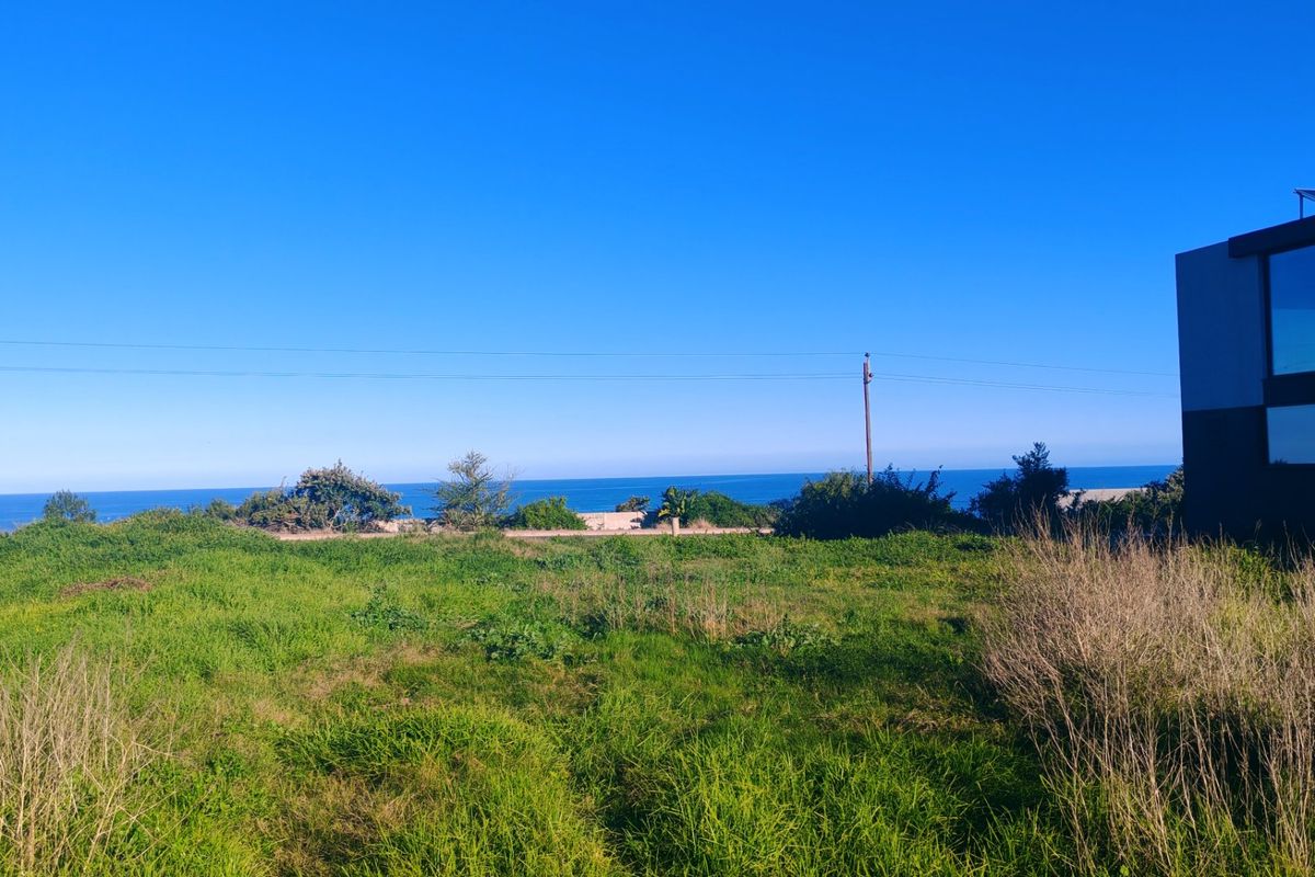 A vacant residential plot featuring expansive ocean views and natural coastal vegetation.
