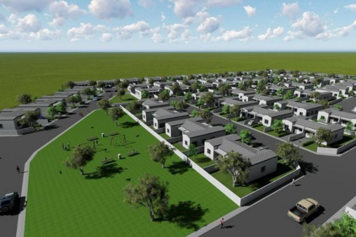 An aerial perspective of a residential development featuring multiple housing units, paved street infrastructure, and a central communal park area.