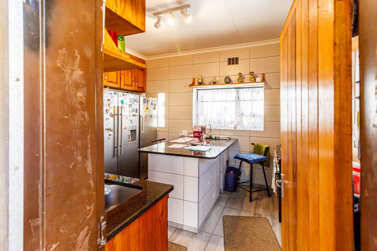 A functional kitchen featuring granite countertops, tiled splashbacks, and built-in cabinetry, offering a practical layout for daily meal preparation.