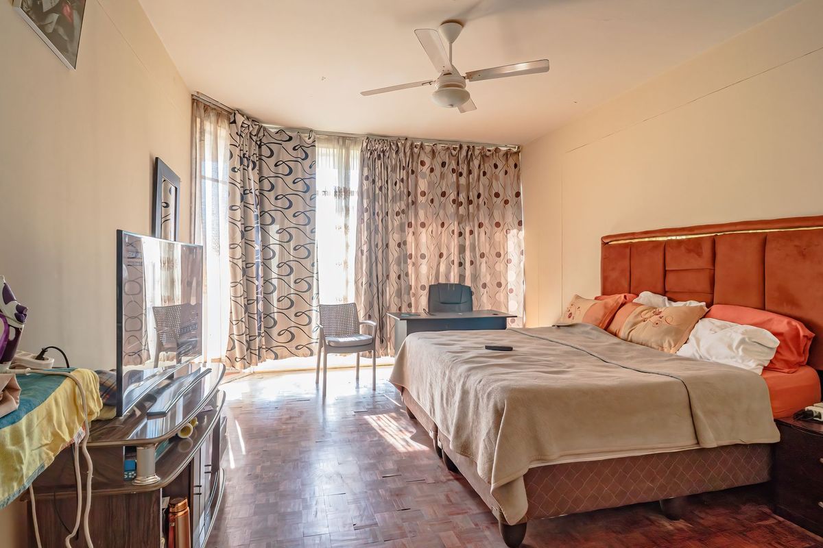 Spacious bedroom featuring parquet flooring, a ceiling fan, and large sliding glass doors that provide natural light.