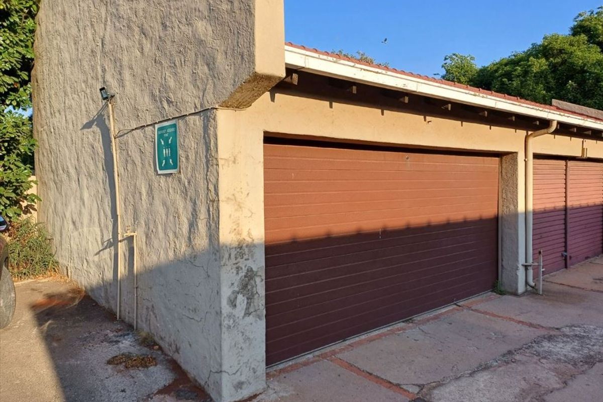 Exterior view of a townhouse garage featuring a sectional door and a weathered concrete driveway.