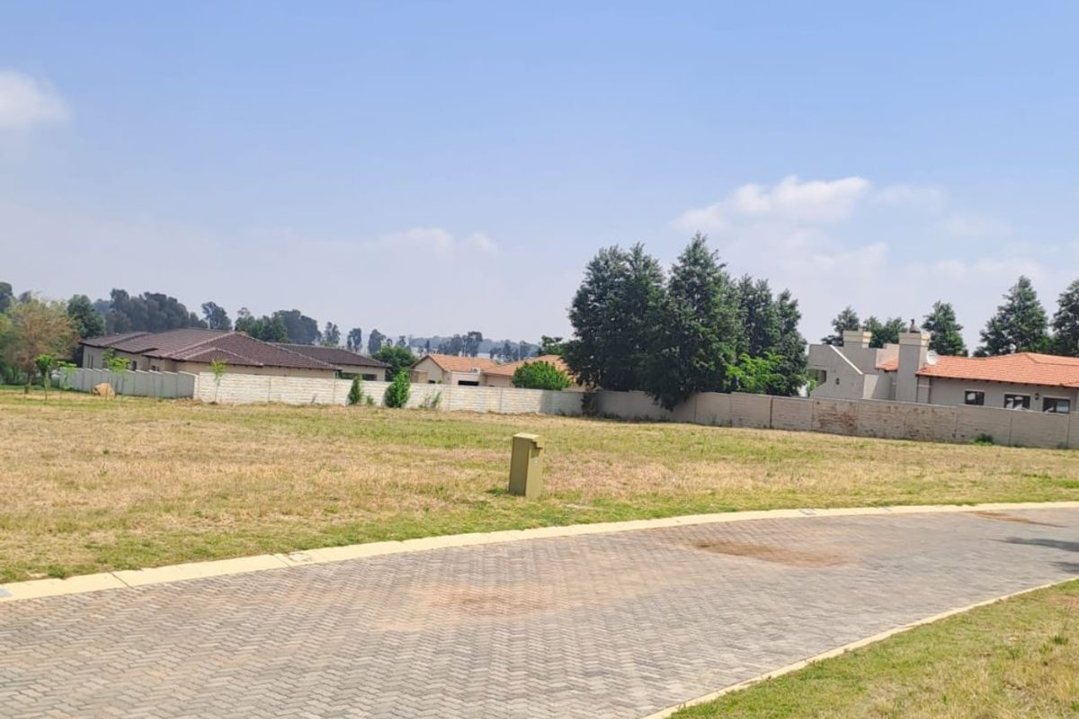 A vacant residential plot featuring a paved driveway, established perimeter walling, and clear access, situated within a developed neighborhood setting.