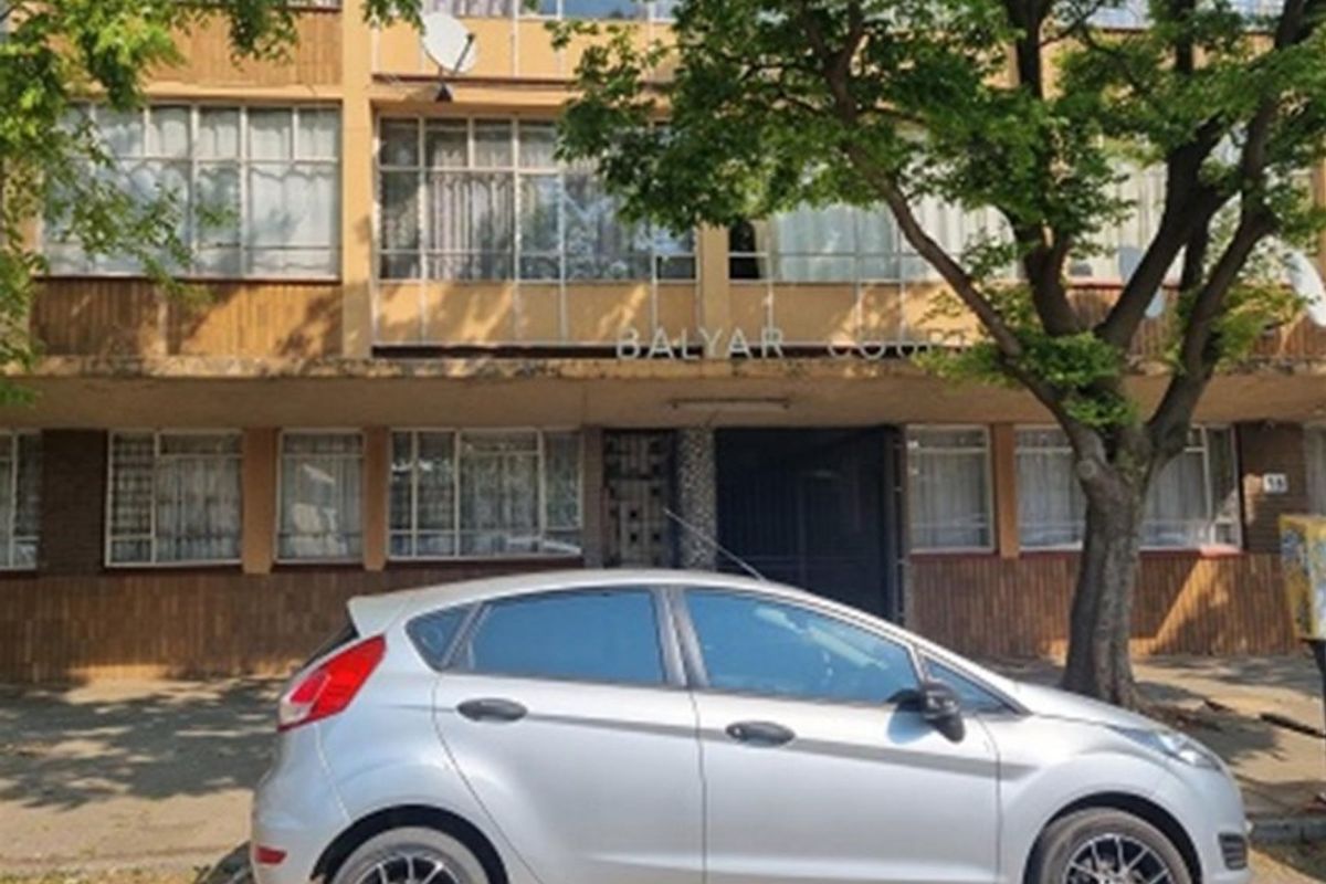 Front elevation of Balyar Court apartment building, featuring a multi-story facade with large windows and visible exterior wear.