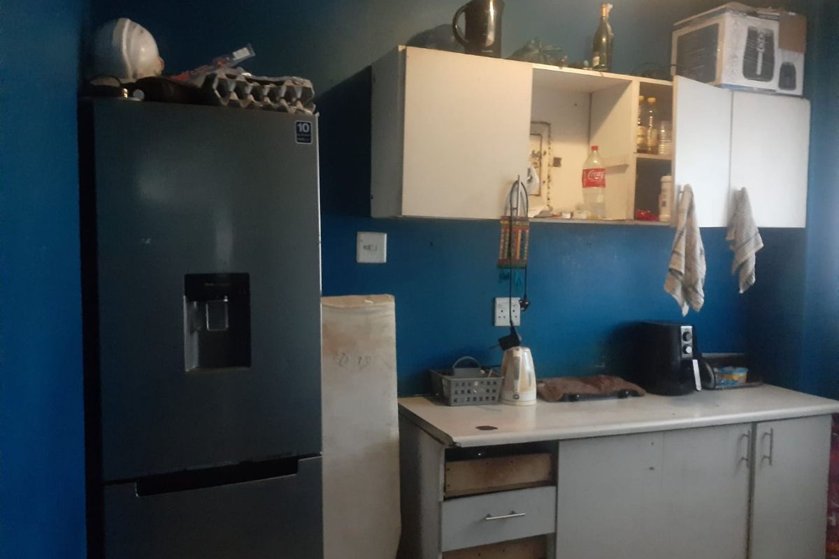 A kitchen area featuring basic cabinetry and countertop space, currently showing signs of wear and requiring maintenance or cosmetic updates.