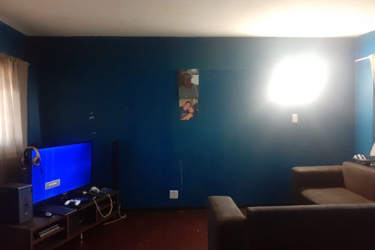 A living room featuring dark blue painted walls and dark flooring, requiring cosmetic updates to improve the overall aesthetic and finish quality.