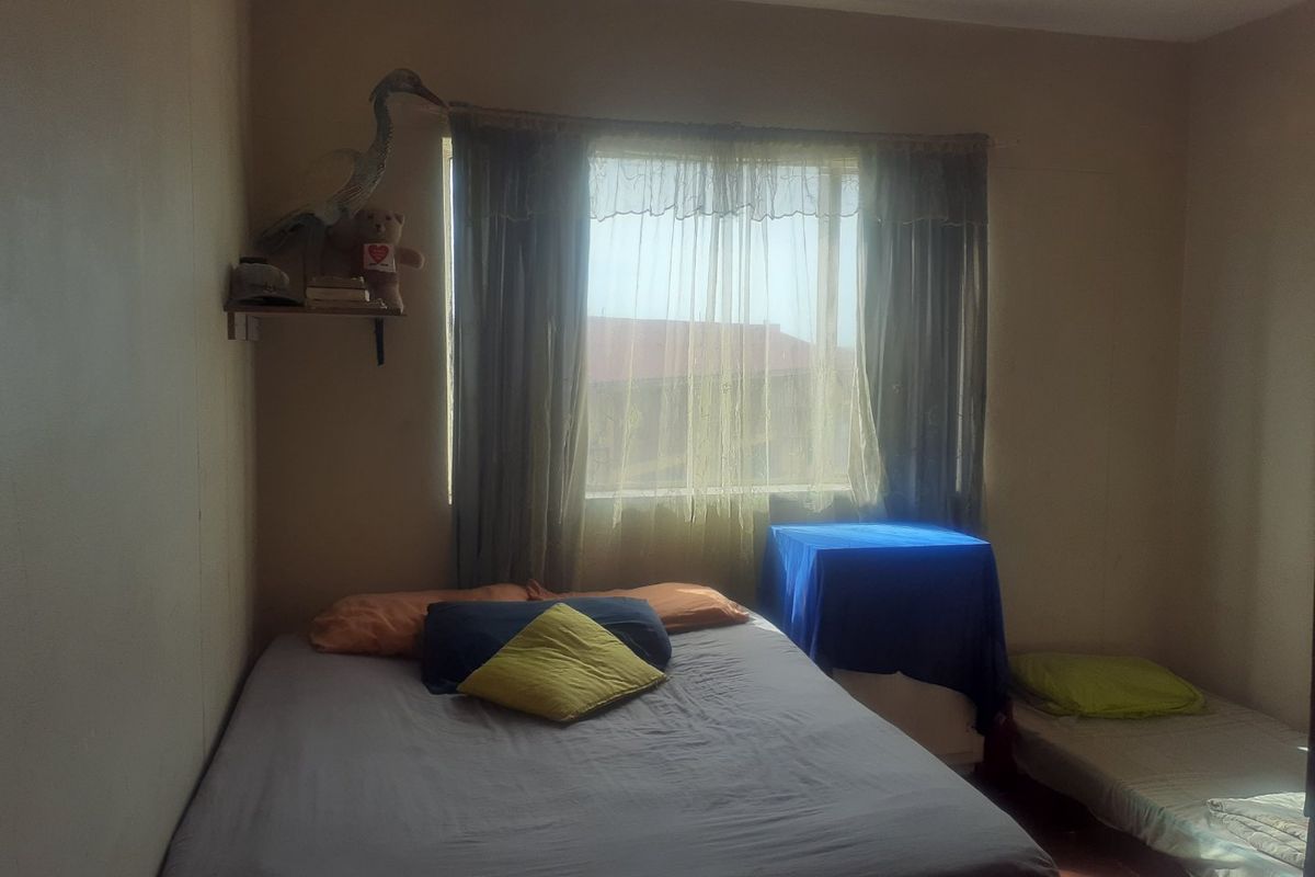 A bedroom featuring a window with curtains, providing natural light. The space requires cosmetic updates to improve its overall appeal and condition.