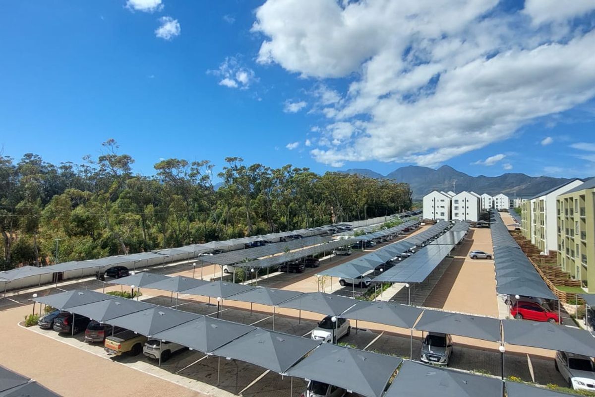 Aerial view of a modern apartment complex featuring extensive covered parking bays and well-maintained residential buildings under a clear sky.