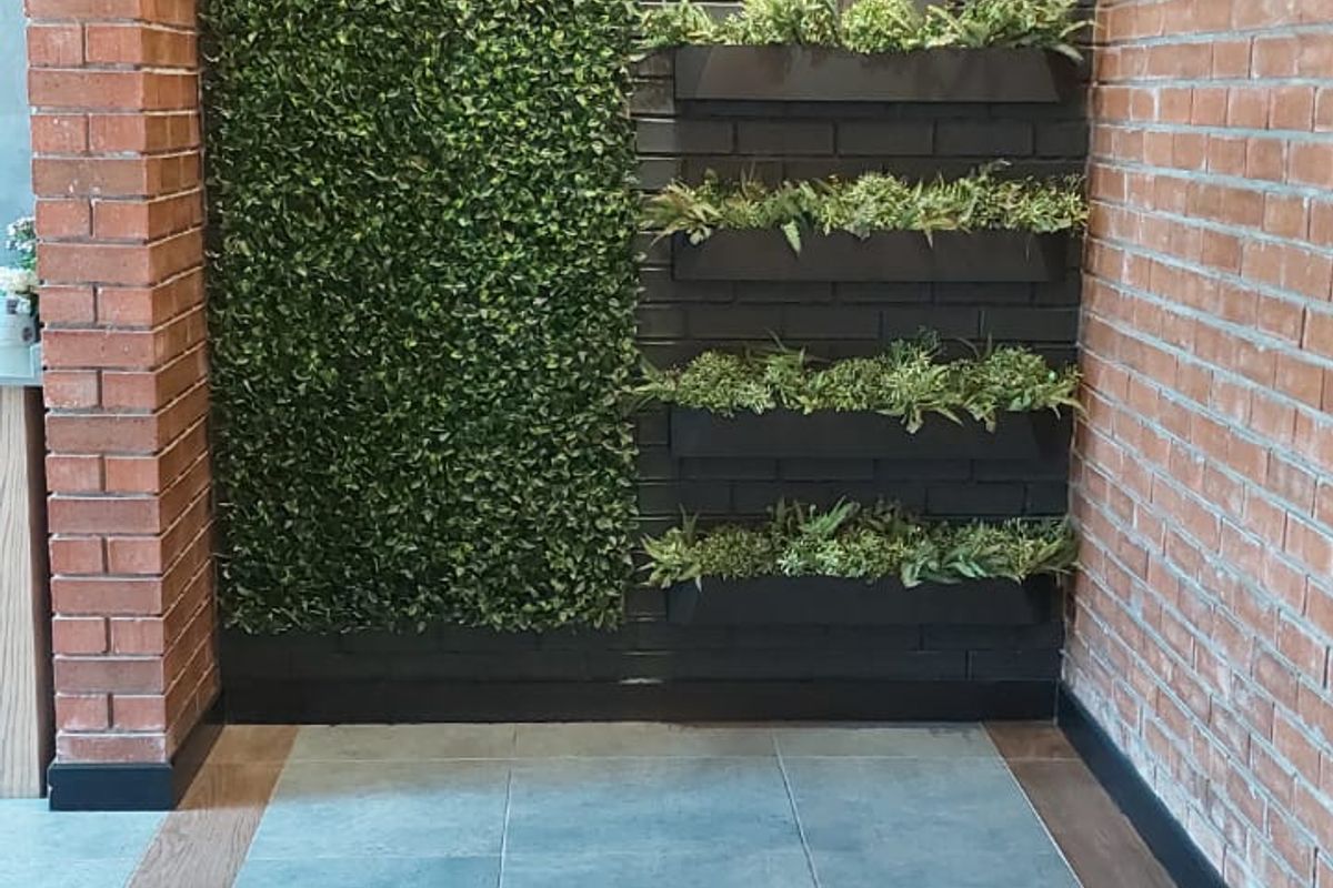 A modern hallway featuring exposed brick walls, decorative vertical greenery, and stylish pendant lighting with tiled flooring.