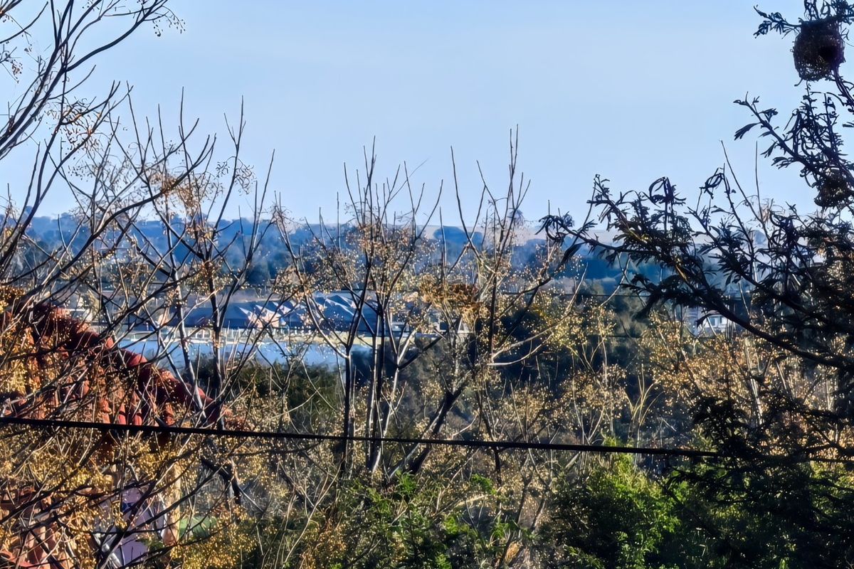 A scenic view overlooking a landscape with distant buildings and natural vegetation.