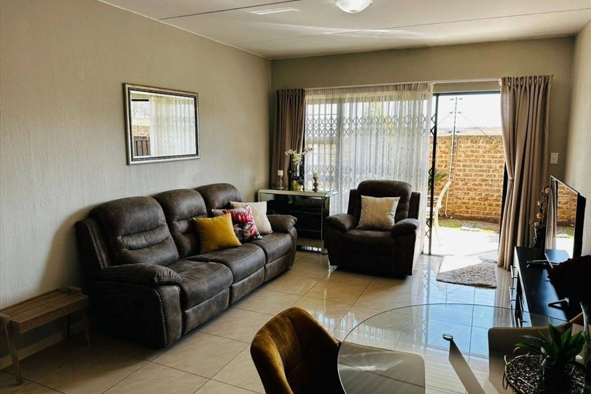 A comfortable living room featuring tiled flooring and a sliding glass door that provides direct access to the rear patio area.