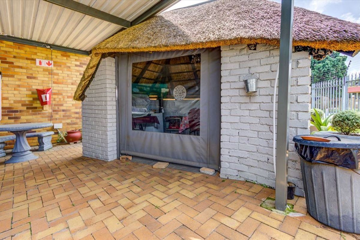 Covered outdoor patio area featuring brick paving and a traditional thatched roof structure with a protective canvas enclosure.