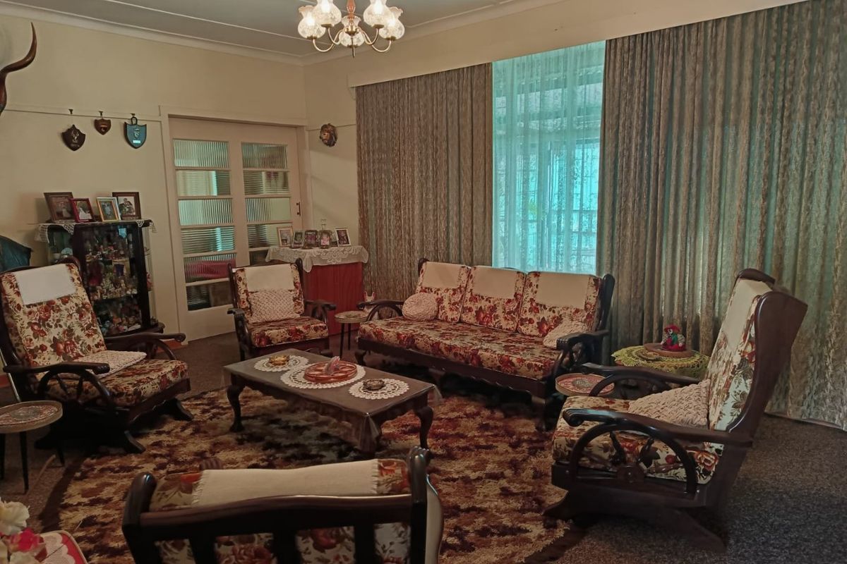 A traditional living room featuring classic french doors and large window treatments, offering a dated but functional space ready for modernization.