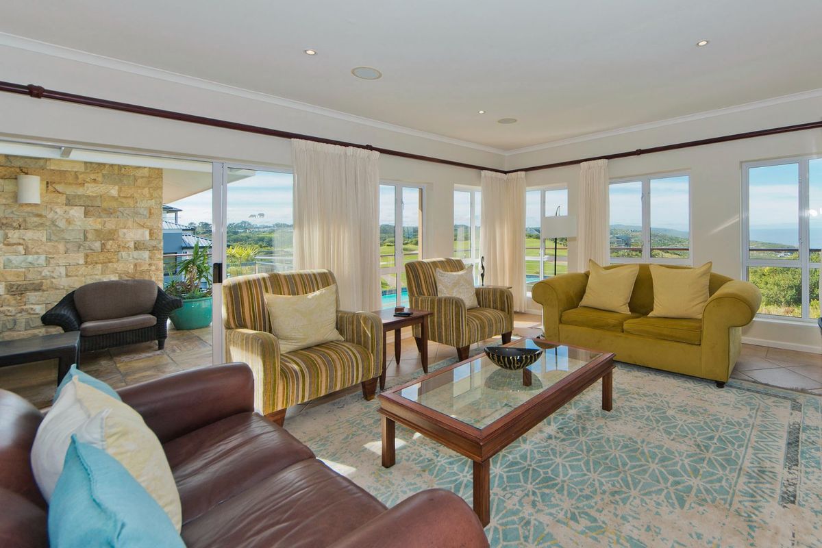 Spacious living room featuring large sliding glass doors, stone accent wall, and tiled flooring with abundant natural light and scenic views.