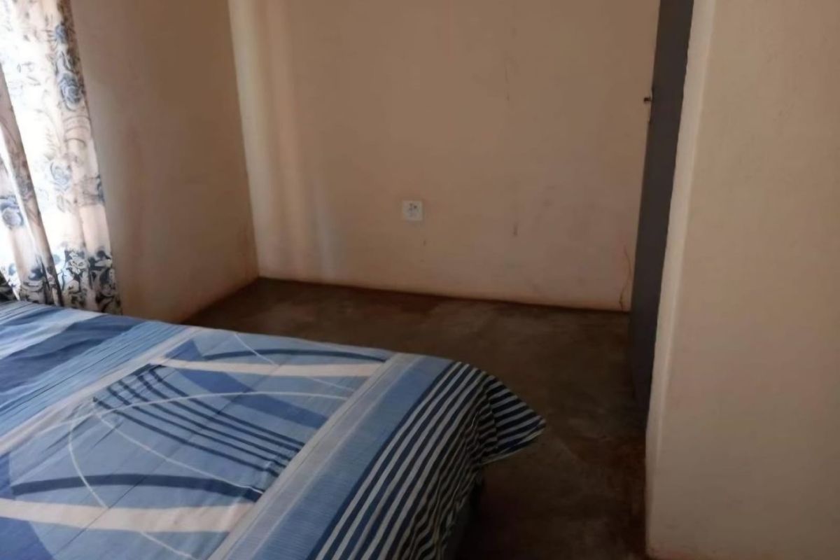 A bedroom featuring plain walls and a basic concrete floor finish, requiring cosmetic updates to improve the overall aesthetic and condition.