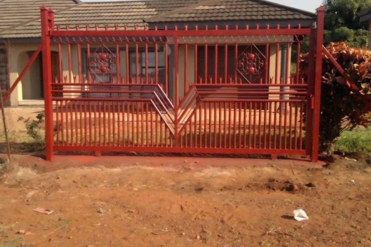 Front view of a residential property featuring a red metal security gate and a tiled roof structure.