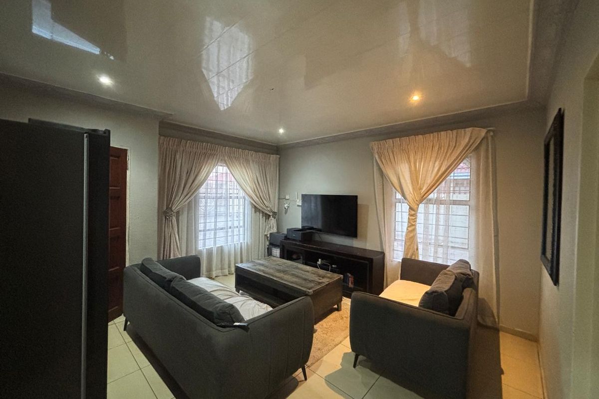 A comfortable living room featuring tiled flooring, recessed downlighting, and a glossy ceiling finish, with security bars installed on the windows.